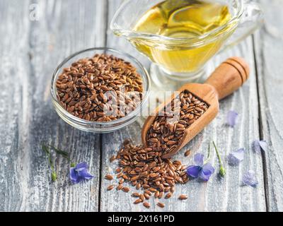 Graines de lin et huile de lin. Graines de lin brunes et huile de lin sur vieux fond de bois gris. Copier l'espace Banque D'Images