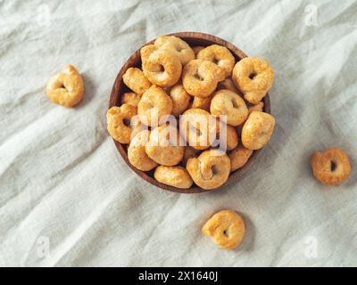 Snack italien traditionnel taralli ou tarallini dans un bol en bois sur fond de serviette en lin léger. Coup rustique de taralli hors-d'œuvre avec espace de copie. Vue de dessus ou à plat. Banque D'Images