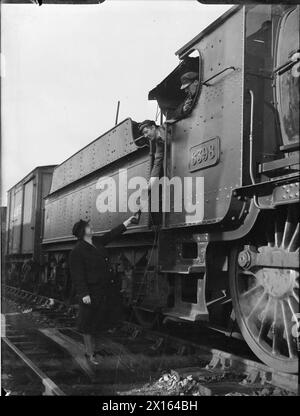 LA FEMME DU SERGENT DU MOYEN-ORIENT FAIT LE TRAVAIL DE SIGNALEUR : LA VIE COMME UN CHEMIN DE FER SIGNALWOMAN, MOLLAND, DEVON, ANGLETERRE, ROYAUME-UNI, 1943 - Signalwoman Daisy Cook remet un « jeton » à un conducteur de train à la gare de Molland dans le Devon. La légende d'origine décrit les systèmes comme suit : « le « jeton » est un disque métallique avec des noms de station dessus. Il est remis au conducteur avant qu'il ne quitte la gare et doit être remis à la gare suivante avant qu'un train puisse partir dans la direction opposée. Comme il n'y a qu'un seul jeton pour chaque tronçon de voie, un seul train peut être sur la voie à la fois.» Banque D'Images