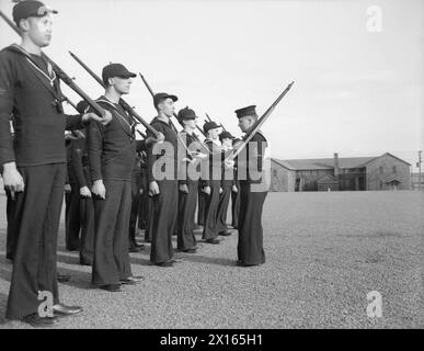 À L'ÉCOLE DES ARTILLEURS TÉLÉGRAPHISTES DE LA ROYAL NAVY AU CANADA. FÉVRIER 1945, YARMOUTH (NOUVELLE-ÉCOSSE). - Des artilleurs de l'air naval en devenir reçoivent une formation disciplinaire du quartier-maître Dowd, de Middlesborough. Ils portent un numéro spécial de couvre-chef d'hiver. Il s'agit de NA2 Truitt et NA2 A Wood de Londres ; NA2 Taylor de Worcester ; NA2 R Wood de Birmingham ; NA2 Radford de Street, Somerset ; et NA2 Webber de Winnipeg, Canada Banque D'Images