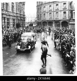 Des membres des Forces françaises de l'intérieur (FFI) défilent dans les rues d'Arras dans des véhicules allemands capturés, acclamés par les civils locaux. Les prisonniers allemands sont escortés le long des rues tricolores dans des camions allemands. Une foule se rassemble alors qu'un jeune homme dévisage un portrait d'Hitler. Banque D'Images