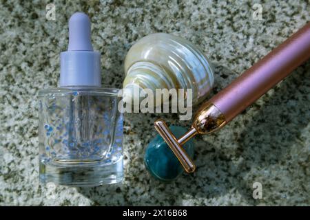 Un T-masseur facial électrique doré sur un podium en pierre. Traitement de beauté maquette de produit anti-âge sur un bord de mer. Vacances d'été cosmétique. Banque D'Images