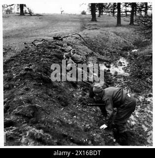 Une patrouille se met à l'abri dans un fossé tandis que des correspondants de guerre observent lors d'une visite au Commandement de l'est. Banque D'Images