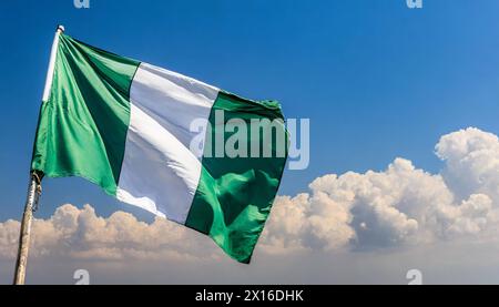 Die Fahne von Nigeria flattert im Wind, isoliert gegen blauer Himmel Banque D'Images