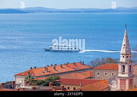 Zadar, Croatie - 15 avril 2019 : clocher du équipé Église François et couvent (croate : Convento di S. Francesco) avec un ferry passant derrière. Banque D'Images