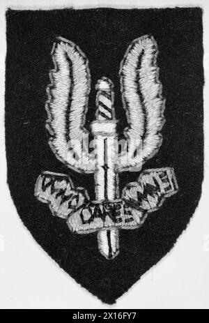 LE SERVICE D'AIR SPÉCIAL (SAS) - le badge de capuchon en tissu du SAS. Dans un effort pour consolider l'identité de sa nouvelle unité, le colonel Stirling a organisé en privé que cet insigne soit fabriqué par un tailleur du Caire. L'écusson de la casquette a été conçu à l'origine comme une épée flamboyante de Damoclès, mais a fini par être un poignard ailé. La devise « Who Dares Wins » résume le concept SAS original de Stirling de l'armée britannique, Special Air Service Banque D'Images