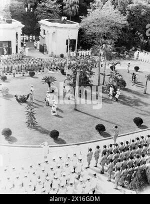 CÉRÉMONIE DE REDDITION DE HONG KONG. LE 16 SEPTEMBRE, LORSQUE LE CONTRE-AMIRAL C. H. J. HARCOURT, CB, CBE, ACCEPTE LA REDDITION INCONDITIONNELLE DE TOUTES LES FORCES JAPONAISES À HONG KONG LORS D'UNE CÉRÉMONIE DANS LA MAISON DU GOUVERNEMENT. - Les marins britanniques et les Royal Marines présentent des armes alors que l'Union Jack est hissé à Government House après la cérémonie de reddition Banque D'Images