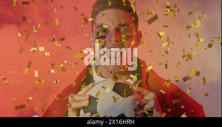 Image de confettis dorés sur un fan de football masculin caucasien acclamé avec drapeau de la peinture du visage de l'allemagne Banque D'Images