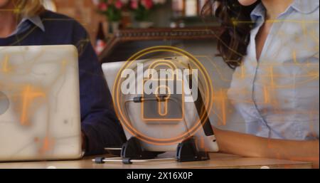 Image de cadenas de sécurité et de traînées de lumière sur une femme biraciale à l'aide d'une tablette numérique dans un bar. Cybersécurité et concept de technologie d'entreprise Banque D'Images