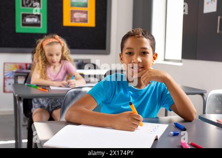 À l'école, en classe, un garçon biracial et deux filles caucasiennes se concentrent sur leur travail Banque D'Images