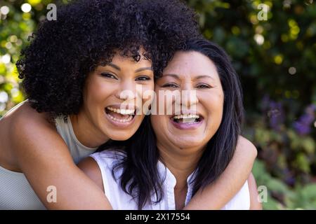 Mère biraciale et fille adulte rient ensemble à l'extérieur à la maison dans le jardin Banque D'Images