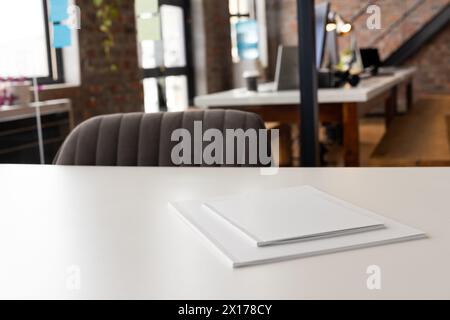 Espace de bureau vide avec bureau blanc au centre, papiers reposant sur le dessus Banque D'Images