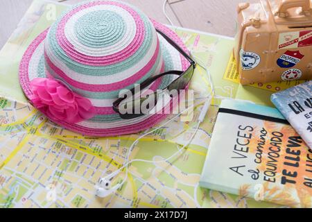 La carte, la valise, le chapeau rose, les lunettes et les écouteurs pour le téléphone sont nécessaires pour un voyage d'été en Espagne. Banque D'Images