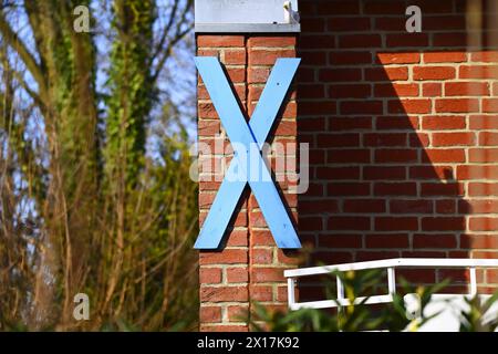 Blaues Holzkreuz als Protestzeichen gegen den Bau des Fehmarnbelttunnels an einem Haus in Haffkrug, Schleswig-Holstein, Deutschland *** Croix bleue en bois comme signe de protestation contre la construction du tunnel Fehmarnbelt sur une maison à Haffkrug, Schleswig Holstein, Allemagne Banque D'Images