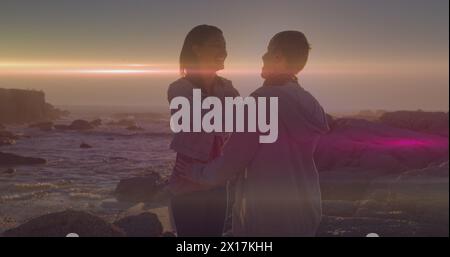 Image de taches lumineuses sur un couple caucasien à la plage Banque D'Images