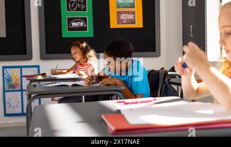 À l'école, en classe, un groupe diversifié de jeunes étudiants se concentrant sur leur travail Banque D'Images