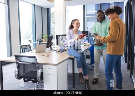 Équipe diversifiée partageant des idées au bureau, femme caucasienne montrant tablette Banque D'Images