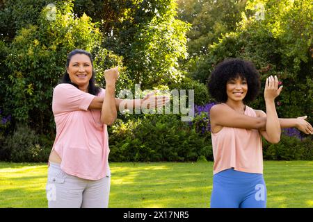 Femme biraciale mature et jeune femme biraciale exerçant dans le jardin à la maison Banque D'Images