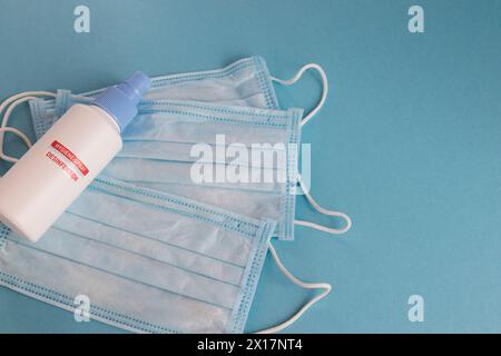 Spray de désinfection et masque médical pour l'hygiène sur le fond bleu avec place pour le texte. Antibactérien, contre la pollution ou protection contre les virus. COVI Banque D'Images