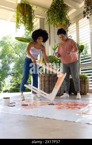 Mère biraciale et fille adulte peignent des meubles ensemble à la maison pour un projet d'upcycling Banque D'Images