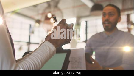 Image de taches lumineuses sur un homme biracial commandant au café Banque D'Images