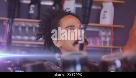 Image de taches lumineuses sur un homme biracial travaillant au café Banque D'Images