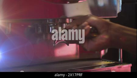 Image des taches de lumière sur l'homme biracial à l'aide d'une machine à café Banque D'Images