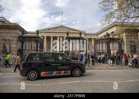 Londres, Angleterre - L'entrée emblématique du British Museum avec des visiteurs et un taxi noir classique au premier plan par temps nuageux. Banque D'Images