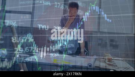 Image du globe, graphiques, tableau de trading sur l'homme d'affaires asiatique réfléchi analysant le plan Banque D'Images