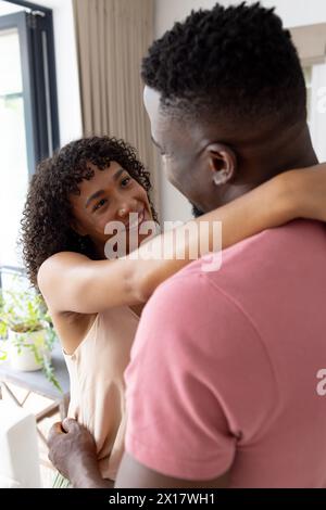 Couple diversifié embrassant, souriant l'un à l'autre à l'intérieur Banque D'Images