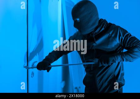 Intrus utilisant un pied-de-biche sur une porte la nuit Banque D'Images