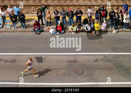 Un coureur du marathon de Boston fait son chemin sur Commonwealth, Avenue à Boston, Massachusetts comme vu d'un appartement au-dessus. Banque D'Images