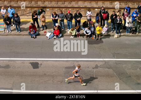 Un coureur du marathon de Boston fait son chemin sur Commonwealth, Avenue à Boston, Massachusetts comme vu d'un appartement au-dessus. Banque D'Images