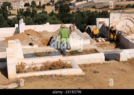 Meknès, deux hommes s'occupent de tombes dans un cimetière traditionnel à ciel ouvert, au nord du Maroc, au Maroc Banque D'Images