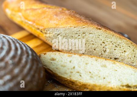 Une tranche de baguette fraîchement cuite coupée sur une planche à découper en bois. Foyer sélectionné. Photo de haute qualité Banque D'Images