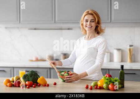 Femme enceinte préparant une salade saine dans la cuisine Banque D'Images