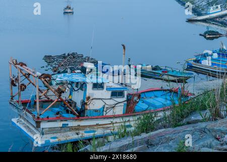 Bateaux de pêche amarrés dans un port au crépuscule, entourés de roseaux et d'eaux réfléchissantes, en Corée du Sud Banque D'Images