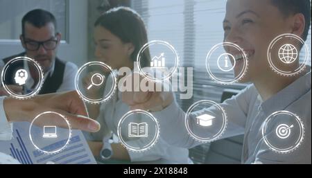 Image de plusieurs icônes numériques contre une femme biraciale poing heurtant un collègue masculin au bureau Banque D'Images