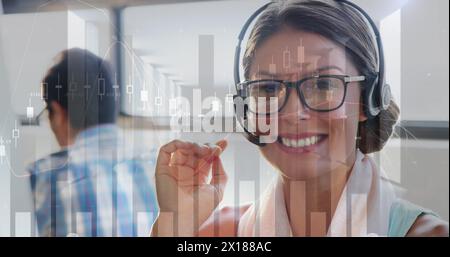 Image de graphiques financiers sur une consultante femme caucasienne heureuse au bureau. commerce, finance, connexions, technologie et interface numérique numériquement Banque D'Images