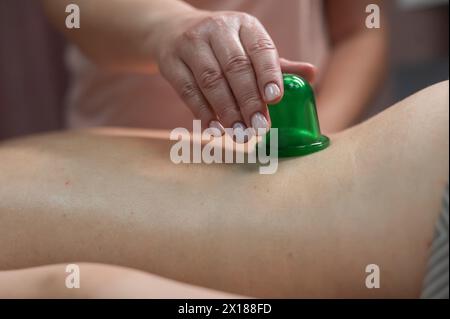 Une femme subit une procédure de massage anti-cellulite à l'aide d'un pot à vide. Gros plan du bas du dos. Banque D'Images