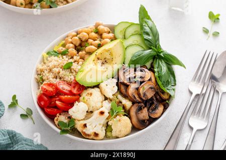 Bol à lunch végétalien sain avec des aliments riches en protéines, des champignons cuits, des pois chiches et du quinoa, et des légumes frais Banque D'Images