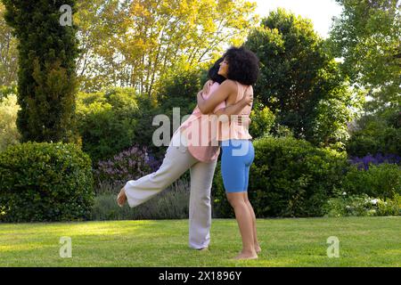 Femme biraciale mature embrassant la jeune fille adulte dans le jardin à la maison Banque D'Images