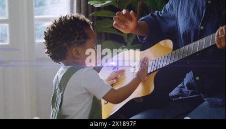 Sur cette image, une jeune mère noire et son fils jouent de la guitare ensemble dans leur salon Banque D'Images