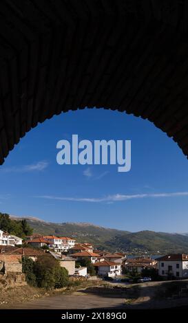 Bâtiments résidentiels avec des toits en céramique en terre cuite et chaîne de montagnes vus à travers une arche de brique, ville d'Ohrid, Macédoine Banque D'Images