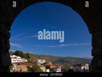 Bâtiments résidentiels avec des toits en céramique en terre cuite et chaîne de montagnes vus à travers une arche de brique, ville d'Ohrid, Macédoine Banque D'Images