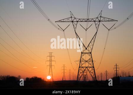 Les tours de transmission de l'électricité hydro qui se profile dans le champ au coucher du soleil en automne, Québec, Canada Banque D'Images