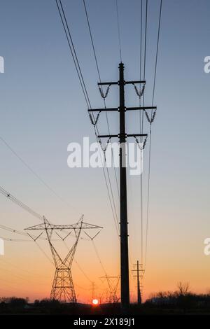 Les tours de transmission de l'électricité hydro qui se profile dans le champ au coucher du soleil en automne, Québec, Canada Banque D'Images