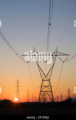 Les tours de transmission de l'électricité hydro qui se profile dans le champ au coucher du soleil en automne, Québec, Canada Banque D'Images