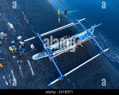 Les pêcheurs déchargent leurs prises de leur bateau en porte-à-faux le matin. Amed, Karangasem, Bali, Indonésie Banque D'Images