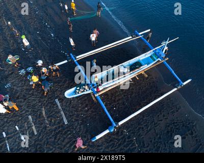 Les pêcheurs déchargent leurs prises de leur bateau en porte-à-faux le matin. Amed, Karangasem, Bali, Indonésie Banque D'Images